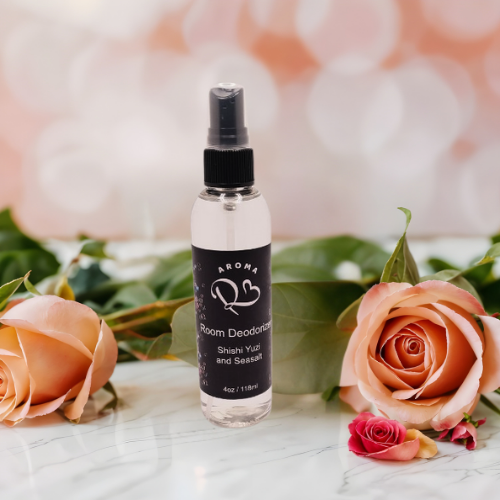 Room deodorant spray bottle with floral arrangement on a marble surface